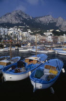 Marina Grande harbour with fishing boats moored in front of buildings with mountains rising behind themEuropean Italia Italian Southern Europe Scenic