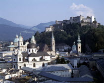 Hohensalzburg Fortress beyond town rooftops with wooded hills behind