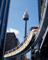 Mono rail train between skyscrapers with Sydney Tower behind.