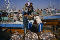 Workers unloading fish from boat on docks