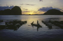 Fish farm at sunset with two men in a canoe