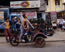 Man riding motorbike laden with beer bottles advertising posters Saigon