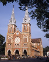 Notre Dame Cathedral twin spires rose window street market people Saigon