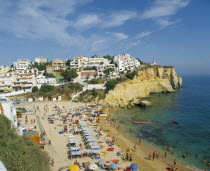 White painted town on rocky headland overlooking busy beach.