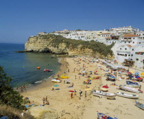 White painted town on rocky headland overlooking busy beach.