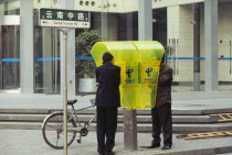 People using city centre public telephone. Center