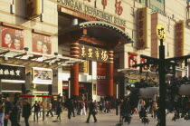 Wanfujing Dajie department store.  Entrance on to busy street with advertising covering exterior wall. Peking Beijing