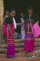 Two Karen women finding their shoes on steps upon leaving a ceremony