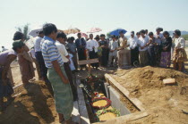 Jinghpaw Baptist funeral service with family gathered around grave near Prayer MountainBurma Myanmar