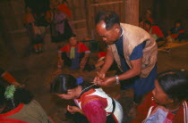 Lisu shaman tying string around supplicants neck at healing ceremony