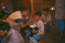 Lisu shaman anointing supplicants head at healing ceremony