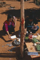 Lisu girl and man burning imitation money beside New Year tree with chicken blood on the trunk