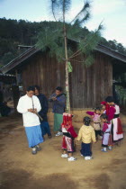 Lisu men play gourd pipes as children dance around the New Year tree