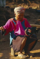 Elderly Lisu woman embroidering a hat for a young boy at her residence