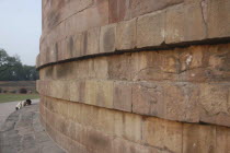 Dhamek Stupa with a Buddhist pilgrim kneeling in prayer at the base