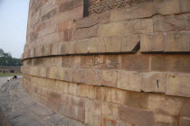 Dhamek Stupa with a Buddhist pilgrim kneeling in prayer at the base