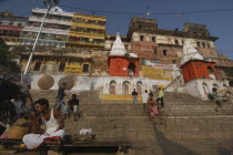 Dasashwamedh Ghat. View looking up at a temple and the houses behind the ghats with a Hindu Bhramin pundit sitting waiting for his next customer on the steps