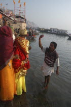 Bhramin pundit or priest at Dashaswamedh Ghat stands in the Ganges River and flicks water in blessing over a bride and groom