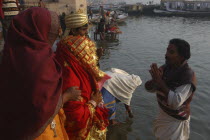 Bhramin pundit or priest stands in the Ganges River at Dashaswamedh Ghat and conducts a prayer for a bride and groom