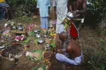 Burial scene with bald headed bereaved son having water poured over him at the grave side