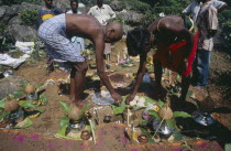 Burial scene with bald headed bereaved son and other people at grave