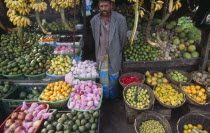 Market vendor standing among his wares on a vegetable stall