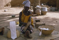 Woman carding cotton before spinning into thread.