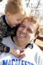 Son talking to dad with arms around his neck.