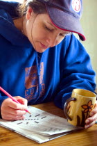 Woman aged 35 working crossword puzzle holding coffee mug.