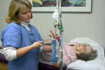 Clinic nurse removing cast from broken wrist of 90 year old patient