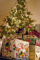 Christmas presents piled high around the decorated evergreen tree. Centre