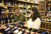 Wine merchant offering bottle of wine to a discerning customer in the Old Vine Wine & Spirits shop located in the Mall of AmericaMOA largest indoor retail and entertainment complex.