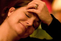 Woman aged 35 smiling and relaxing with her hand on her forehead and her eyes closed