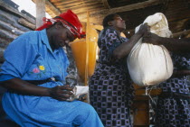 Women lifting up a sack of food aid next to a woman sat writing on piece of paper.Tanzania 96