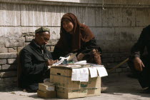 Woman dictating to letter writer at stall outside post office.