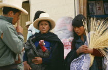 Market scene with woman holding turkey  in conversation with man and another young woman.