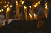 Young girl holding candle lit graveside vigil for Day of the Dead. Dia de los Muertos