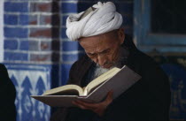 Iman Holyman with head down reading in mosque.