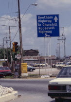 Road scene with large blue and white highway sign.