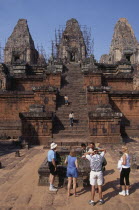 Preah Rup.  Western tourists with guide at cremation pit in foreground of funereal temple undergoing restoration.Asian Cambodian Kampuchea Religion Southeast Asia History Holidaymakers Kamphuchea Rel...