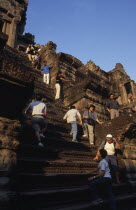 Tourists climbing steep narrow steps to upper or third level. Asian Cambodian Kampuchea Religion Southeast Asia History Holidaymakers Kamphuchea Religious Tourism