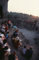 Tourists with cameras watching the sunset from the central sanctuary on the upper level. Asian Cambodian Kampuchea Religion Southeast Asia History Holidaymakers Kamphuchea Religious Tourism