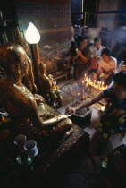 Wat Pho small shrine beside the reclining Buddha with devotees making offerings to small Golden BuddhasAsian Prathet Thai Raja Anachakra Thai Religion Siam Southeast Asia Religious Siamese