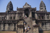 Western tourists climbing steep and narrow set of steps of enclosure wall at the rear of the temple complex. Asian Cambodian Kampuchea Religion Southeast Asia History Holidaymakers Kamphuchea Religio...