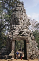 Ta Prohm monastic complex with tourists walking through the four faced west gateAsian Cambodian Kampuchea Religion Southeast Asia 4 History Holidaymakers Kamphuchea Religious Tourism