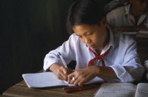 Secondary school student writing at a desk in the classroom