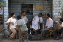 Group of men talking and smoking hookah in a tea shop.