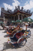 Koo Kongsi  the Dragon Mountain Hall. Exterior of clan house with line of decorated bicycle rickshaws in the foreground.