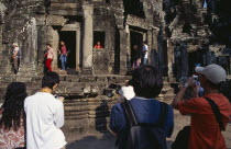 The Bayon.  Tourists posing for photographs amongst the temple architecture.Asian Cambodian Kampuchea Religion Southeast Asia History Holidaymakers Kamphuchea Religious Tourism