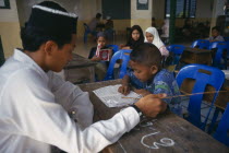 Children studying the Koran at Chiang Mai Mosque under the supervision of a young  male teacher.